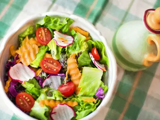 Unas frescas ensaladas de verano con lechuga, tomate, rábano y zanahoria rallada, listas para disfrutar.