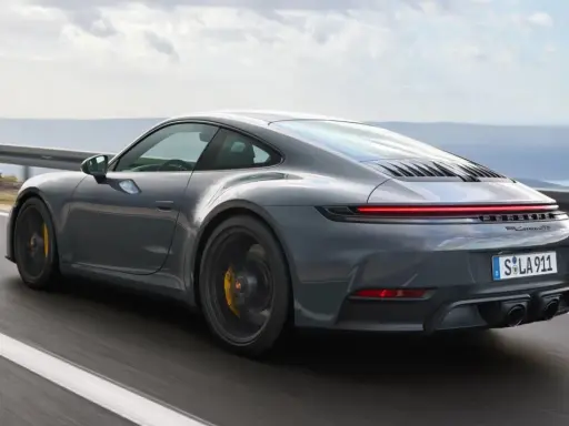 Grauer Porsche 911 Hybrid rast auf einer Küstenstraße.