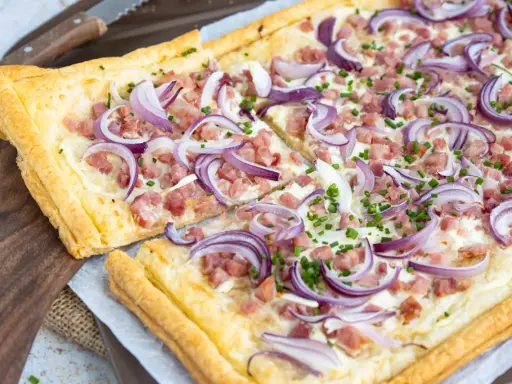 Flammkuchen varianten: knuspriger Teig mit Speck, Zwiebeln und Schnittlauch belegt.