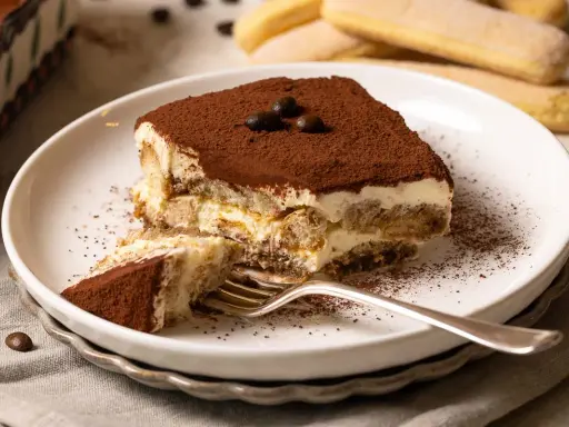 Ein Stück Tiramisu, perfekt für ein Tiramisu Rezept, mit Löffelbiskuit, Creme und Kakaopulver bestäubt.