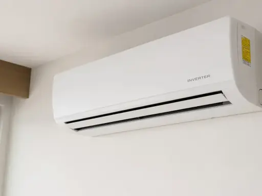 Aire acondicionado blanco con tecnología "INVERTER" montado en pared. Descubre qué significa invertir en aire acondicionado para tu hogar.