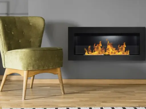 Sillón verde junto a chimenea moderna encendida. Un ejemplo de como encender la chimenea para crear un ambiente acogedor.