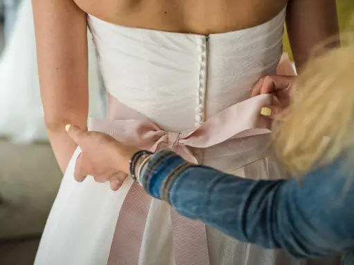 Pomoc w zawiązaniu paska od sukienki, tworząc piękny kokardę na plecach.