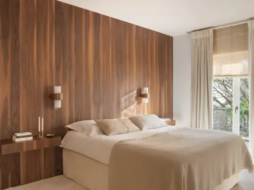 Dormitorio con cabecero de madera natural, creando un ambiente sereno y un cabecero feng shui. Cama confortable con mantas cálidas y luz tenue.