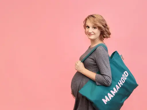Przyszła mama z torbą "Mamahood" zastanawia się, kiedy spakować torbę do szpitala.