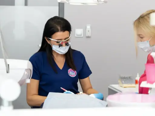 Dentystka w okularach i masce pracuje przy pacjencie. Dyskutują, jak przyspieszyć schodzenie znieczulenia.