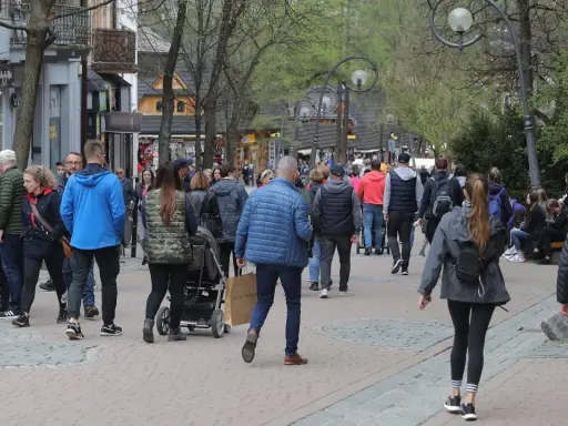 Spacer po Krupówkach, gdzie można spotkać znanych ludzi z Zakopanego. Tłum turystów i mieszkańców przemierza deptak.