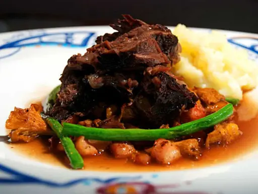 En härlig tallrik med långkokt oxkind, kantareller, gröna bönor och potatismos. Ett perfekt oxkind recept för en festmåltid.
