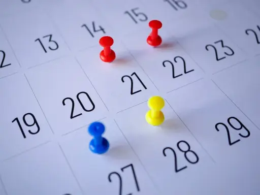 Kolorowe pinezki na kalendarzu pokazują, jak liczyć urlop wypoczynkowy. Planowanie wolnego czasu staje się prostsze.