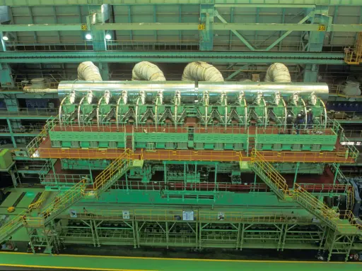 Vue aérienne d'un moteur de bateau massif, le plus gros moteur de bateau jamais construit, avec des ouvriers inspectant son imposante structure verte et argentée.