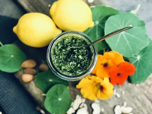 Frisches Pesto aus Kapuzinerkresse, garniert mit Zitronen, Nüssen und Blüten. Ein Genuss zum Kapuzinerkresse essen!