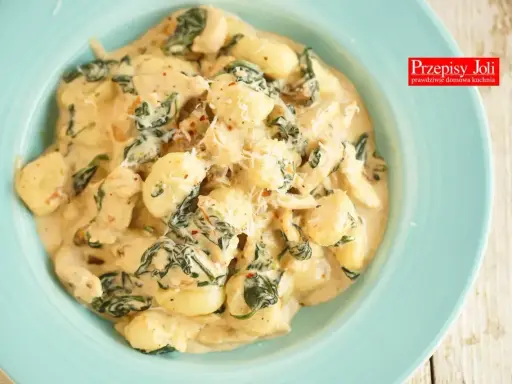 Pyszne gnocchi z kurczakiem i szpinakiem w kremowym sosie, posypane parmezanem. Idealne danie na szybki obiad.