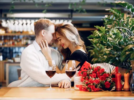 Para świętuje 13 rocznicę ślubu w restauracji, z kieliszkami wina i bukietem czerwonych róż.