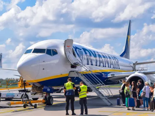 Samolot Ryanair na płycie lotniska z pasażerami i obsługą.