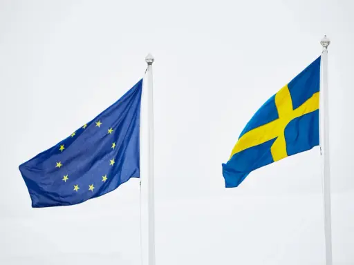 Sveriges flagga och EU-flaggan vajar sida vid sida. En symbol för samarbete inom europeiska unionen.