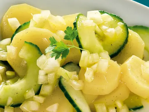 Ein köstlicher Kartoffelsalat mit Gurken, garniert mit Petersilie.
