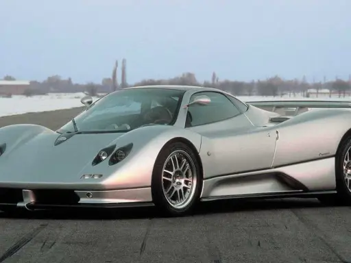 Silberner Pagani Zonda C12 steht auf einer Straße, im Hintergrund verschneite Bäume und Gebäude.