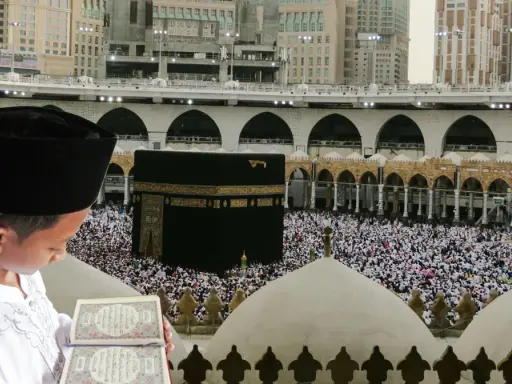 Chłopiec w czapce i białej szacie czyta Koran na tle tłumu pielgrzymów i Kaaby w Mekce.