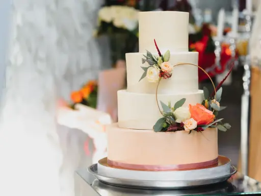 Czteropiętrowy tort weselny w pastelowych kolorach, ozdobiony świeżymi kwiatami i złotym pierścieniem. To najmodniejsze najpiękniejsze torty weselne.