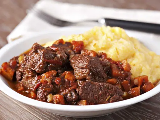 Un plat de daube de sanglier sans marinade, mijoté avec des légumes, servi avec une purée de maïs crémeuse. Un délice !