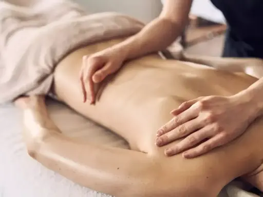 Dłonie terapeuty wykonują relaksacyjny masaż pleców, przynosząc ukojenie i odprężenie.