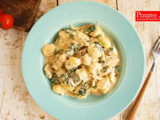 Pyszne gnocchi z kurczakiem i szpinakiem w kremowym sosie, posypane parmezanem. Idealne danie na obiad.