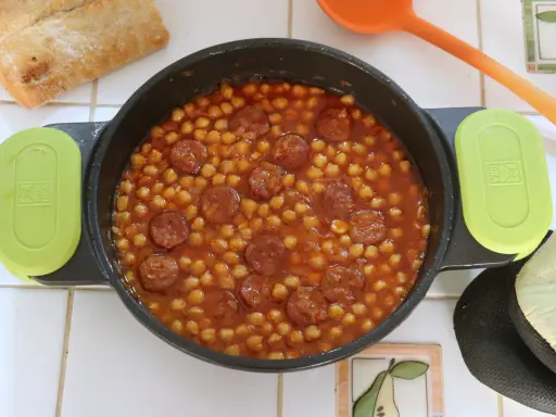 Un plato humeante de garbanzos con chorizo, listo para disfrutar con pan crujiente.