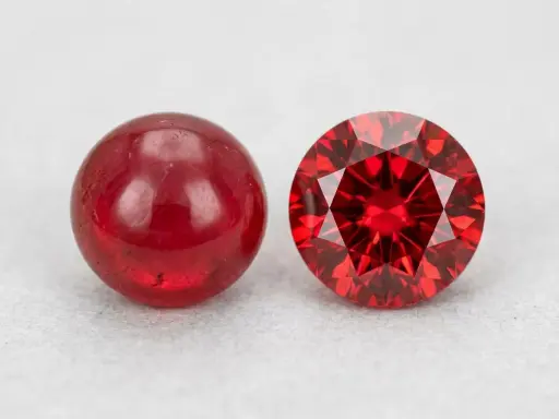 Due pietre rosse brillanti, una liscia e sferica, l'altra sfaccettata e scintillante: il minerale del rubino in due forme.