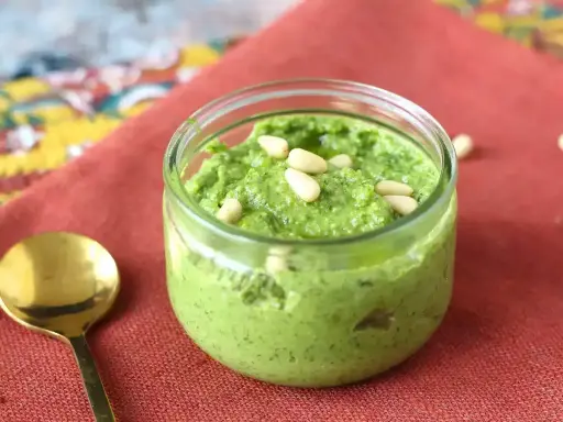 En burk med hemgjord pesto, toppad med pinjenötter. Perfekt för ditt nästa pesto recept!