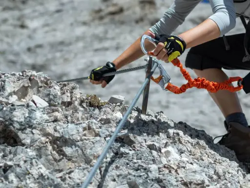Ręce w rękawiczkach trzymają się stalowej liny na via ferrata. To część ekscytujących szlaków na Słowacji.