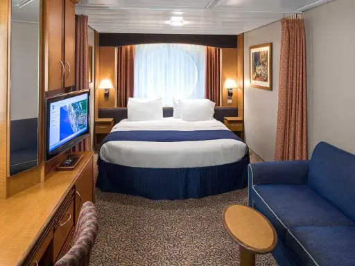 Cabina garantita MSC quando viene assegnata: letto matrimoniale, divano blu, TV e oblò rotondo.