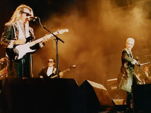Medlemmar av Eurythmics på scen. Dave Stewart spelar gitarr, Annie Lennox sjunger. En saxofonist och en keyboardist syns också.