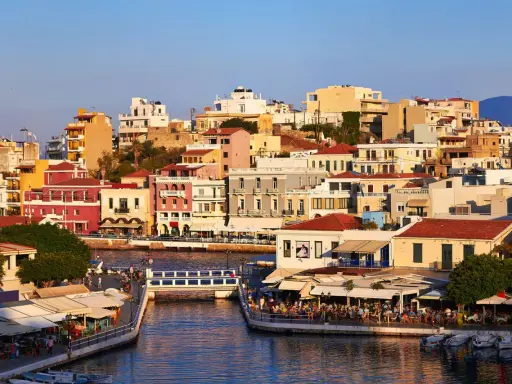 Agios Nikolaos, cosa vedere: un pittoresco porto con case colorate, ristoranti affacciati sull'acqua e un ponte pedonale.