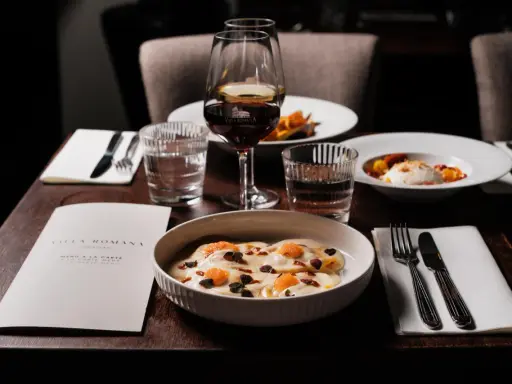 En elegant dukning med italiensk mat, vin och meny från Villa Romana, en av Stockholms bästa italienska restauranger.