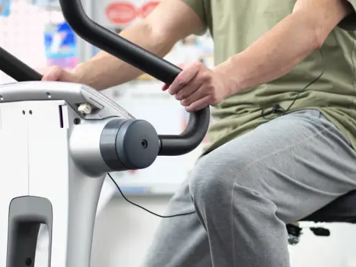 Osoba ćwiczy na rowerku stacjonarnym. Dowiedz się, ile jeździć na rowerku stacjonarnym, aby osiągnąć swoje cele.