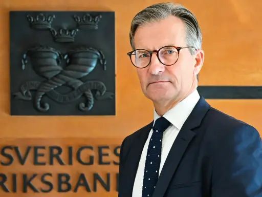 Erik Thedéen, med Riksbankens emblem bakom sig, ser ut som en person som vet hur man hanterar barn och ekonomi.