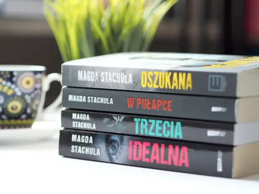 Kolejność czytania książek Magdy Stachuli: "Oszukana", "W pułapce", "Trzecia", "Idealna". Obok filiżanka.