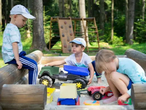 Dzieci bawią się w piaskownicy, ucząc się, jak pomóc dziecku być lubianym przez zabawę i dzielenie się zabawkami.