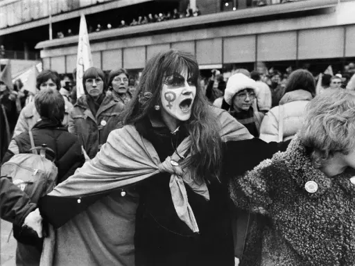 En kvinna med ansiktsmålning och symbolen för kvinnor ropar under en demonstration för sveriges demokratisering.