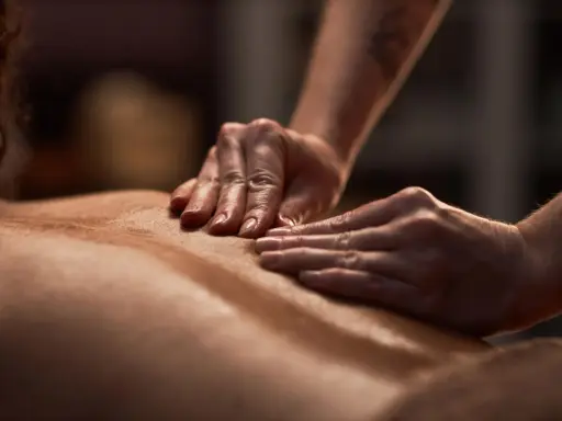 Dłonie terapeuty wykonują relaksujący masaż pleców, ukazując różne rodzaje masażu.