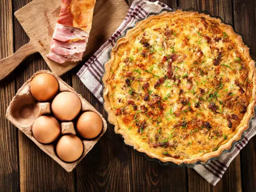Quiche Lorraine, un classique de la gastronomie lorraine, avec ses ingrédients frais : œufs, lardons et herbes.