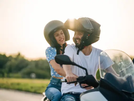 Pareja feliz en moto, disfrutando del atardecer. El sol brilla sobre sus cascos, creando un ambiente de aventura y libertad. CSRNET A2.