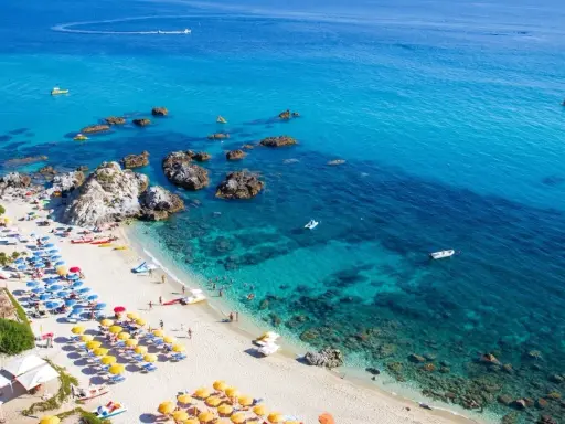 Spiaggia calabrese con ombrelloni colorati e mare cristallino, ideale tra i posti da visitare in Calabria con bambini per una vacanza indimenticabile.