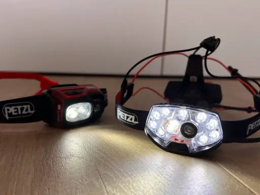 Dwie czołówki Petzl, gotowe na nocne bieganie. Jedna czerwona, druga z wieloma diodami.