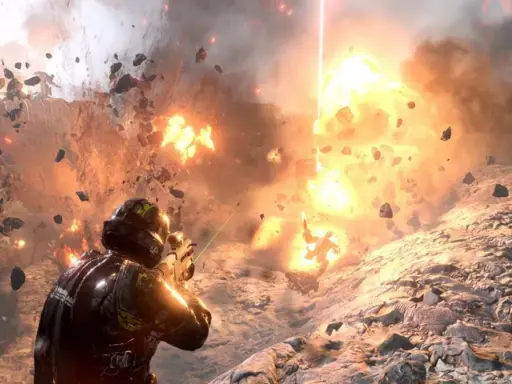 Żołnierz w zbroi walczy w ogniu eksplozji, odłamki skał latają wokół. To scena z gry Helldivers 2.