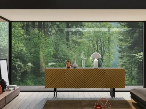 Madia moderna con ante a righe diagonali, un tavolino basso con oggetti decorativi e una grande vetrata su una foresta lussureggiante.