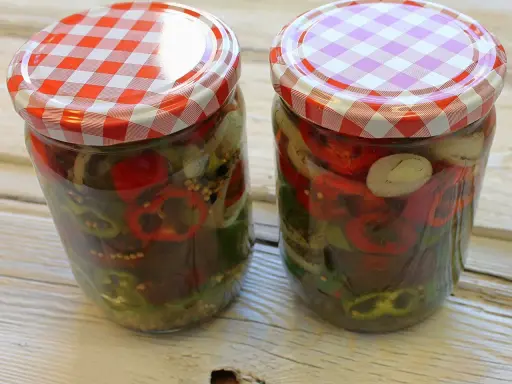 Zwei Gläser mit eingelegten Chilis und Zwiebeln, bereit zum Genießen.