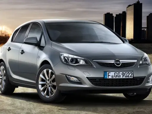 Szary Opel Astra J 1.7 CDTI z nowoczesnymi światłami i felgami, na tle miasta i energetycznego kręgu.