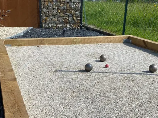 Terrain de pétanque avec boules et cochonnet sur du gravier fin. Le choix du quel sable pour terrain de pétanque est crucial pour un jeu parfait.