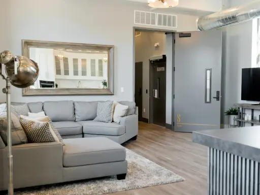 A grey sectional sofa with patterned pillows sits on a rug in a modern living room.